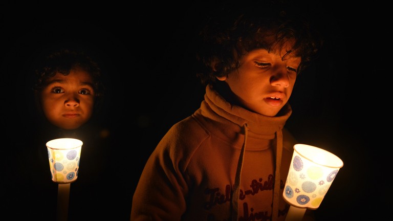 Two young boys holding candles at a vigil for Our Three Winners.
