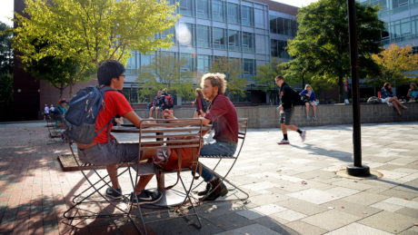 Students chat at an outdoor table on NC State's campus.