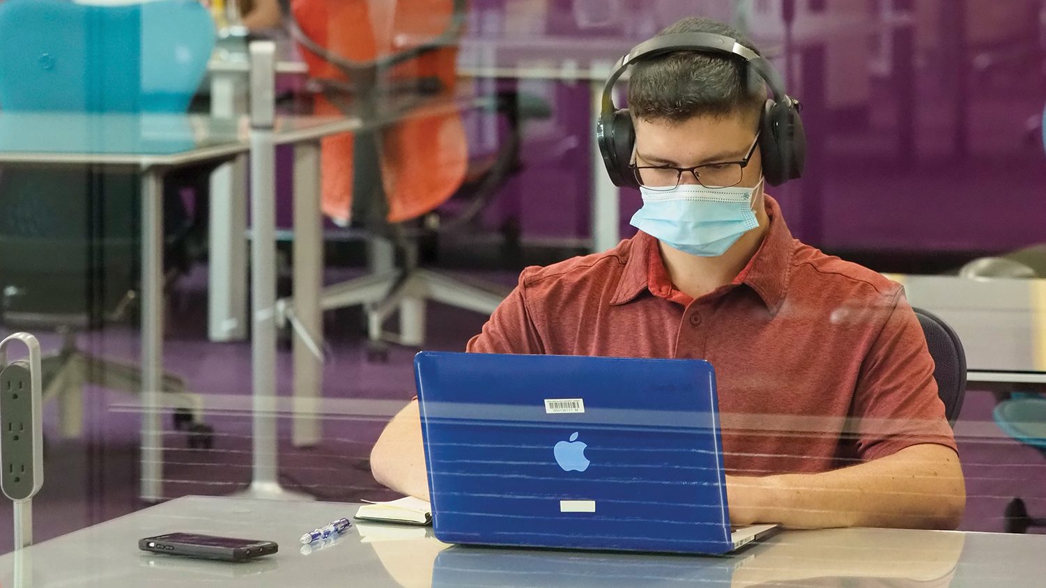 A student wearing a face mask studies in D.H. Hill Library.