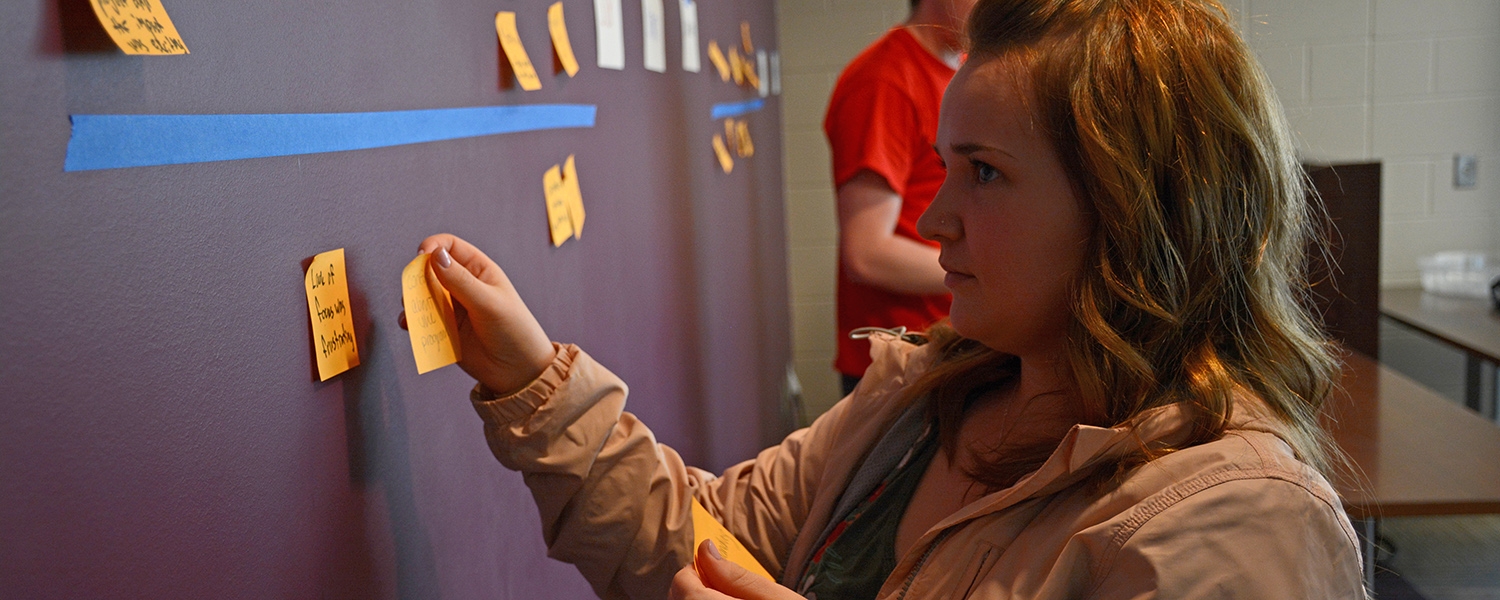 Student places sticky note on the wall