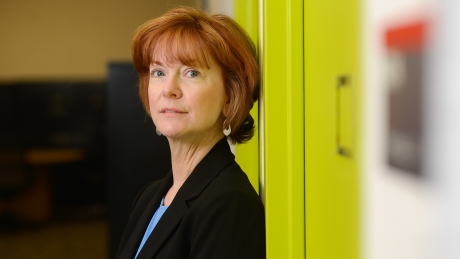 Mary Haskett stands in front of green wall.