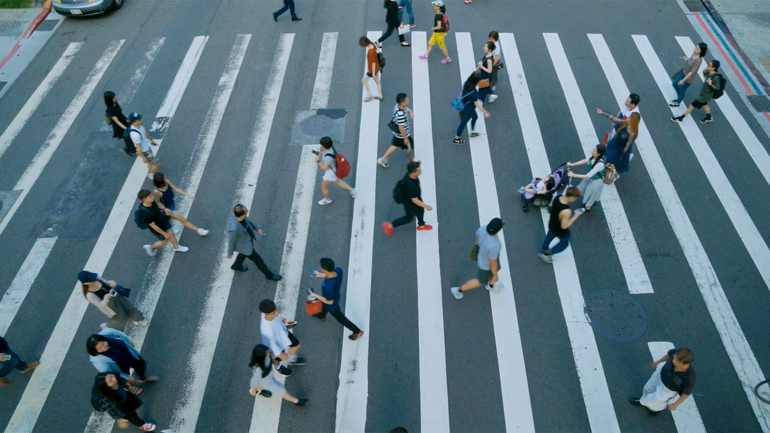 Pedestrians use a large crosswalk to cross the street.