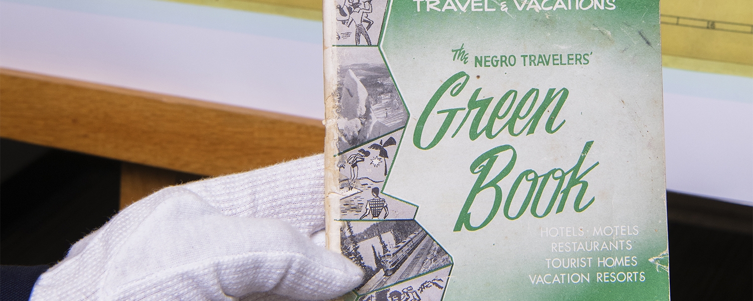 A gloved hand holds a copy of the Green Book