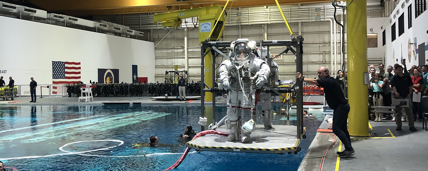 Two astronaut candidates are raised from a buoyancy tank after training