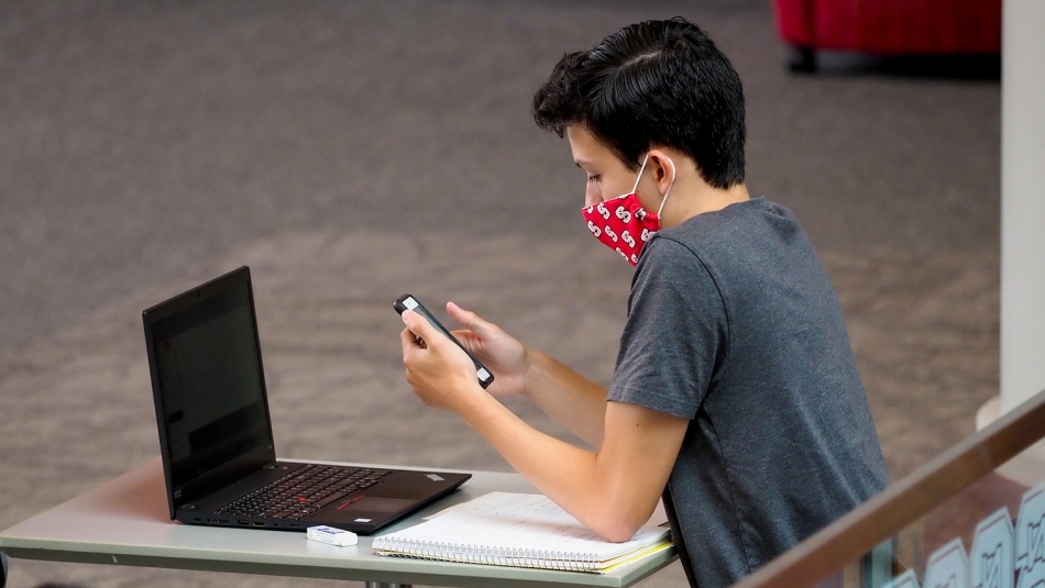 student sitting with phone and laptop in Talley