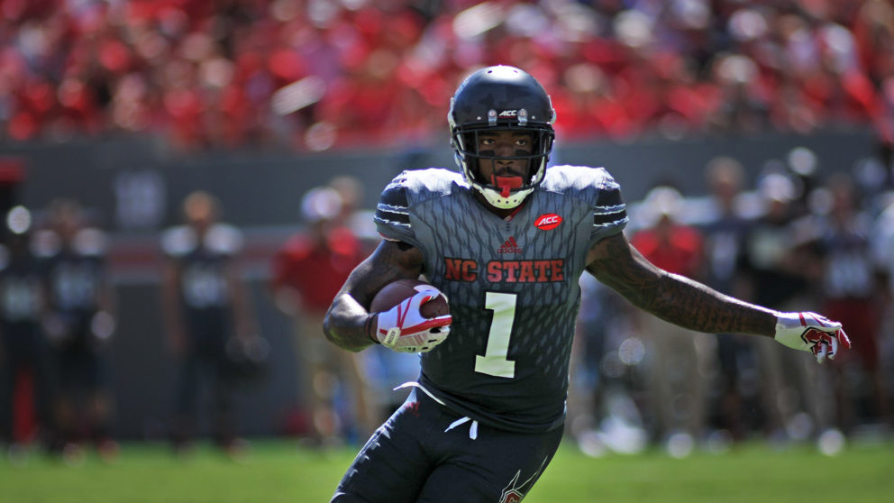 NC State athlete holds a football during a game.