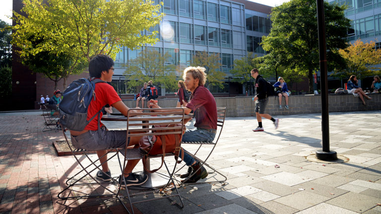 Students chat at an outdoor table on NC State's campus.