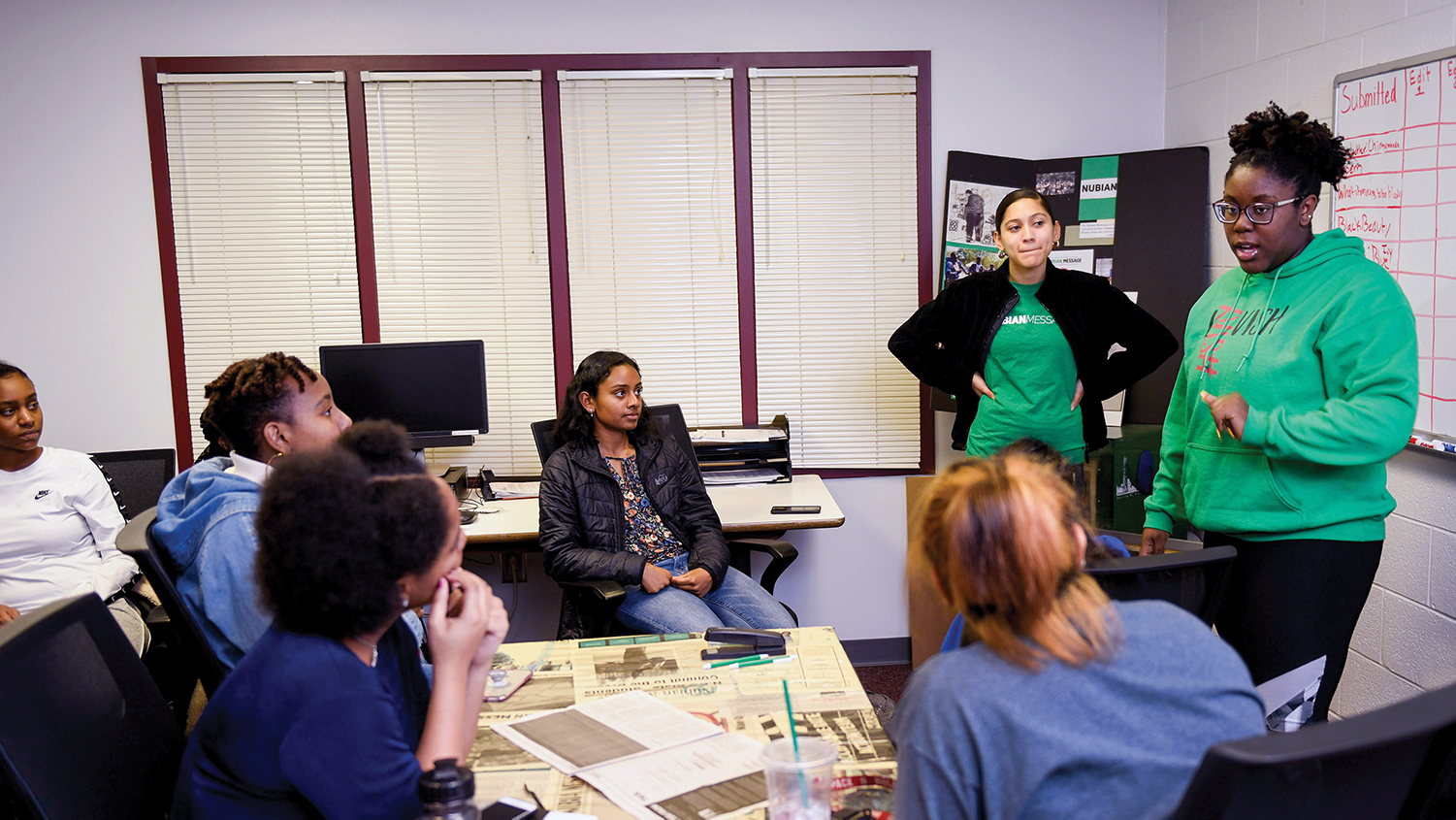 Staff members at the Nubian Message discuss work at a meeting.